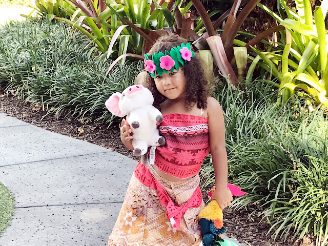 Little girl dressed like Moana holding a Pua plush toy